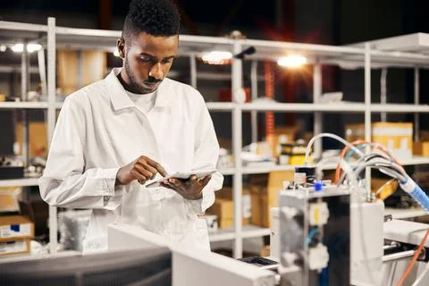 African engineer programming equipment with tablet at factory Stock-Fotos