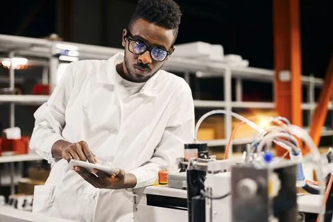 African engineer programming equipment with tablet at factory Stock-Fotos