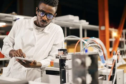 African engineer programming equipment with tablet at factory Stock-Fotos