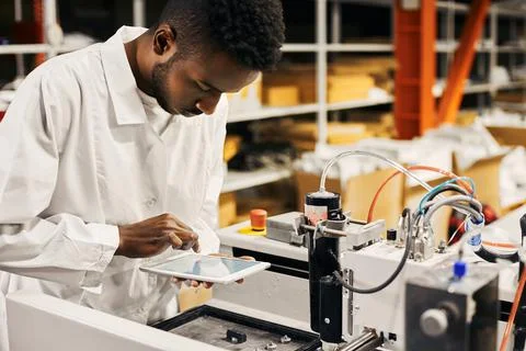 African engineer programming equipment with tablet at factory Stock-Fotos