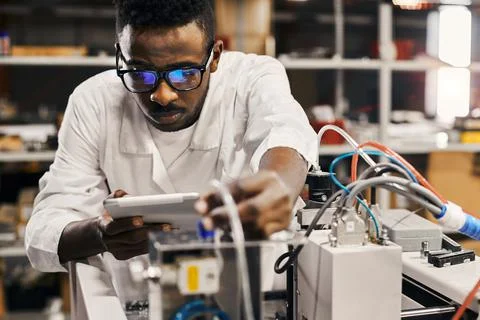 African engineer programming equipment with tablet at factory Stock-Fotos