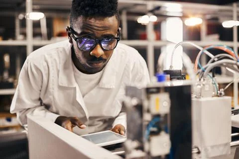 African engineer programming equipment with tablet at factory Stock-Fotos