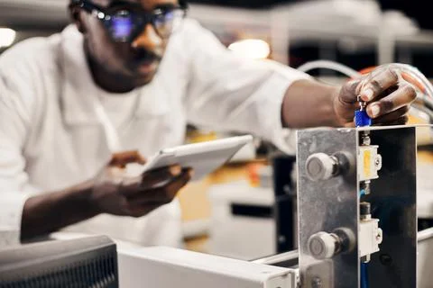 African engineer programming equipment with tablet at factory Stock-Fotos