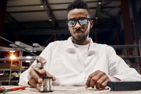 African engineer using soldering iron at factory Stock Photos