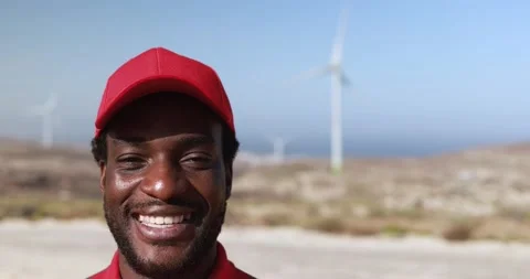 African engineer worker smiling on camera with windmill farm in background Stock Footage 194266433