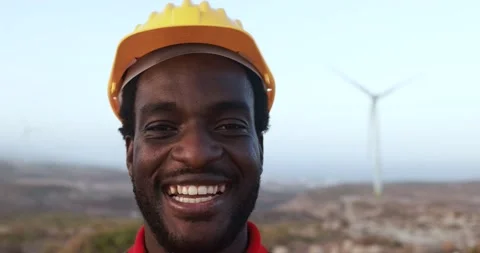 African engineer worker smiling on camera with windmill farm in background Stock Footage 194267336
