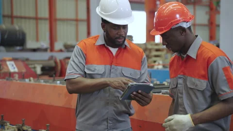 African engineers and workers use tablets to inspect industrial machines. Stock Footage 173079604