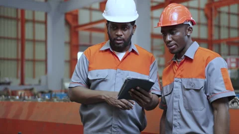 African engineers and workers use tablets to inspect industrial machines. Stock Footage 173080538