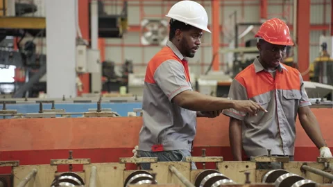 African engineers and workers use tablets to inspect industrial machines. Stock Footage 173375564