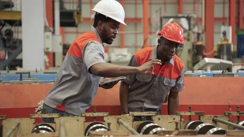 African engineers and workers use tablets to inspect industrial machines. Stock Footage 173375569