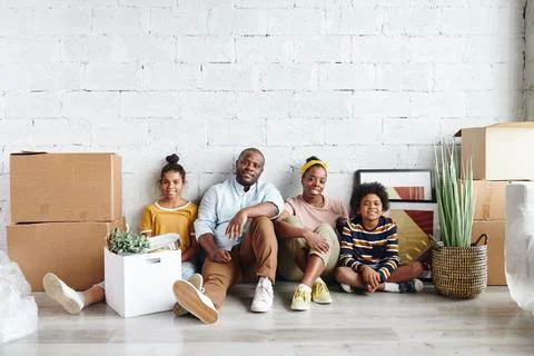 African family of father, mother and two children in casualwear sitting against Stock Photos