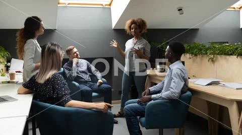African female leader coach mentor talk to multiethnic work group Stock Photos