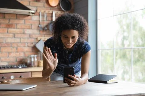 African female lean on table hold smartphone talk by videocall Stock Photos