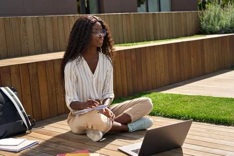 African female student elearning using laptop studying outside campus. Stock-Fotos