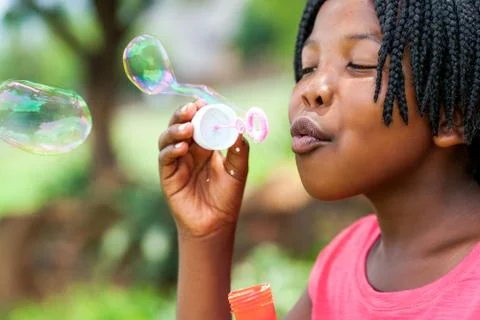 African girl with braids blowing bubbles. Stock Photos
