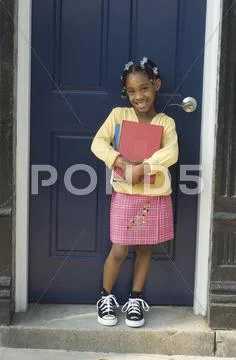 African girl holding school books in doorway Stock Photos