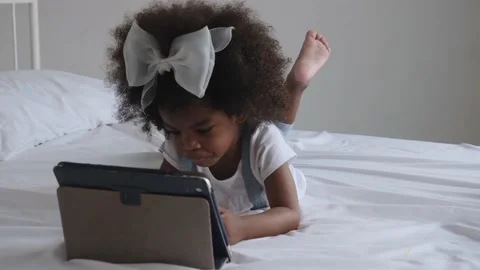 African girl lying on bed, using digital tablet alone. Stock Footage 199083453