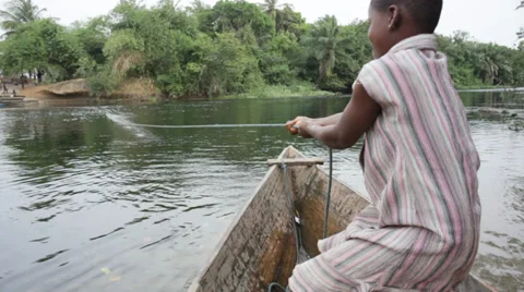 An African girl pulling the rope in a canoe to cross the river Stock Footage 34686392