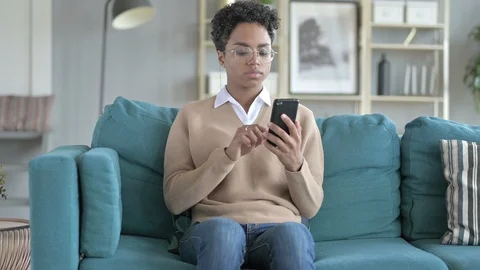 African Girl Using phone while Sitting on Couch Video stock 114783028