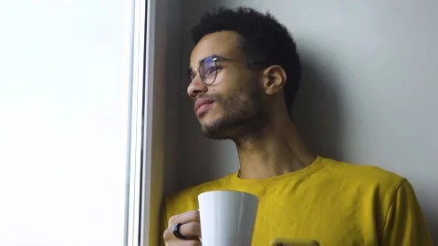 African guy drinking coffee from a mug by the window Stock Footage 164838487