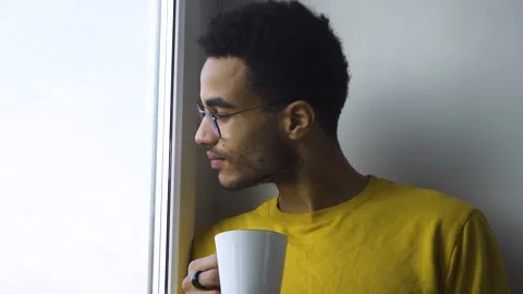 African guy drinking coffee from a mug by the window Video stock 166051772