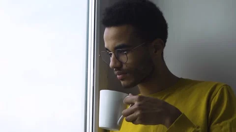 African guy drinking coffee from a mug by the window Stock Footage 171165689