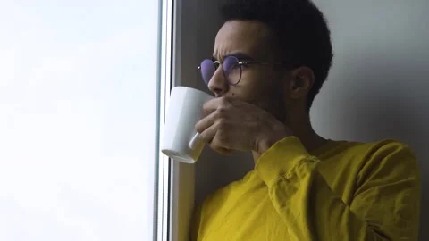 African guy drinking coffee from a mug by the window Stock Footage 171235839