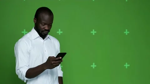 African guy looking with delight at mobile phone on chrome hockey background Stock Footage 130831072