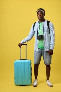 African guy with serious expression posing with suitcase for travel on camera Stock Photos