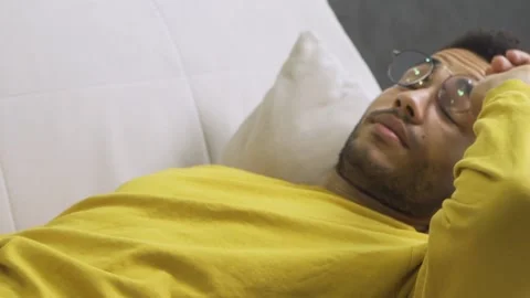African guy is tired lying on the couch Stock Footage 179971406