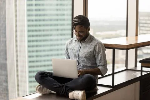African guy working remotely sit cross-legged with laptop Stock Photos