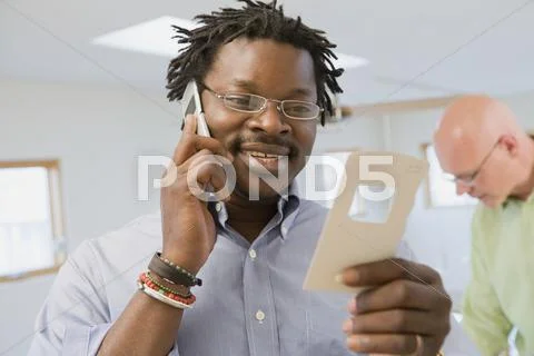 African Interior Designer Looking At Paint Swatch And Talking On Cell Phone