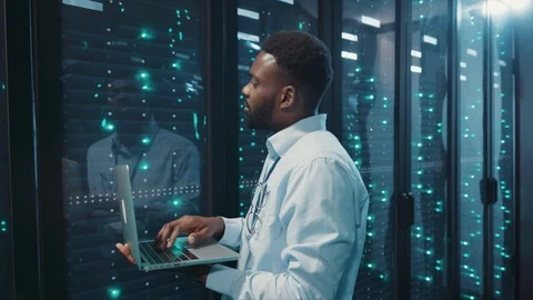 African IT administrator using notebook monitoring working server computers on Stock Footage 119082090