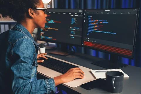 African IT developer concentrating codding program on laptop screen. Tastemaker. Stock Photos