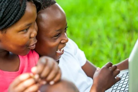 African kids having fun on laptop outdoors. Stock Photos