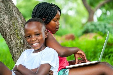 African kids under tree with laptop. Stock Photos
