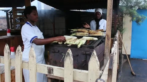 African ladies smiling while roasting corn to sell in market Stock Footage 47885890