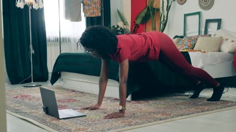 African lady is doing exercises at home with her laptop. Sport at home, fitness Stock Footage 267528737