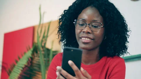 African lady is entering card data into her phone and smiling Stock Footage 267529376