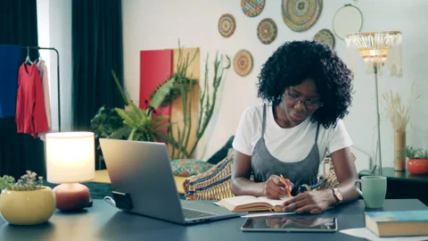 African lady is working with a book during a videocall at home. Online learning Stock Footage 267529613