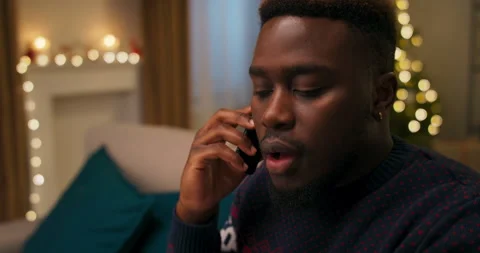 An African-looking guy is talking on phone with friend. He heard the terrible Stock Footage 211062434
