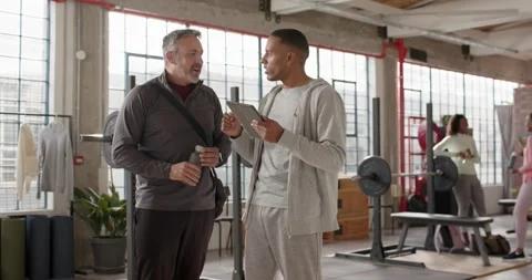 African male trainer-client at loft gym tapping tablet causing nodding fist Stock Footage 337255236