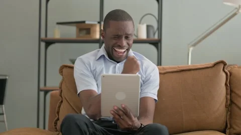 African Man Cheering Win on Tablet while Sitting on Sofa at Home Stock-Footage 287914605
