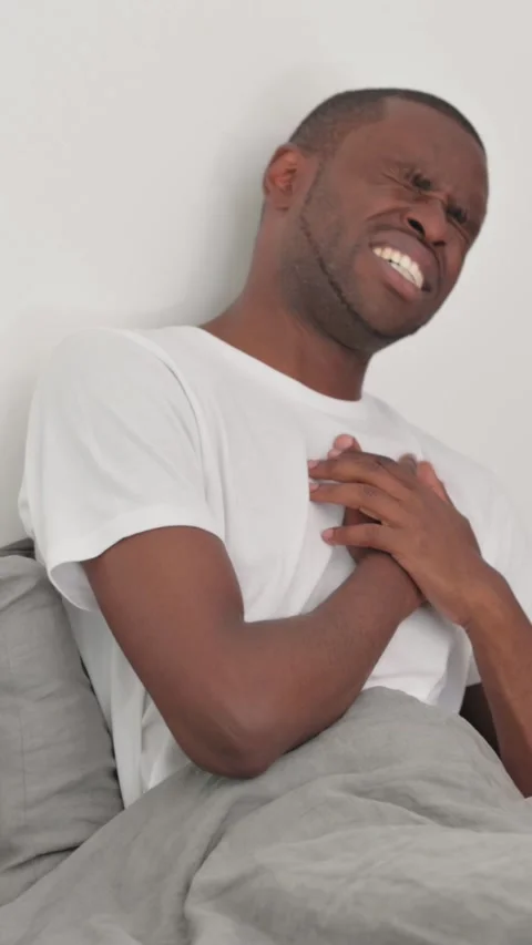 African Man with Chest Pain while Sitting in Bed Stock Footage 301855596
