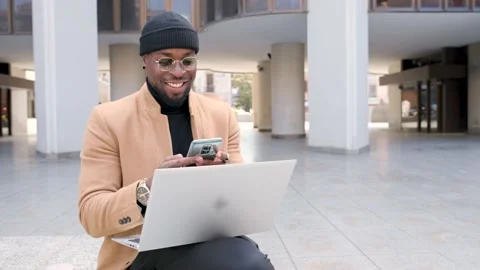 African man in the city using computer laptop and smartphone Stock Footage 157323033