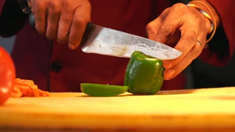 African man cutting vegetables with a sharp knife using a yellow cutting board Stock Footage 230080414