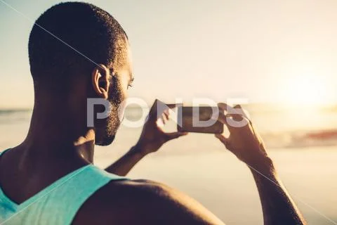 African man doing mobile photography on the beach Stock Photos