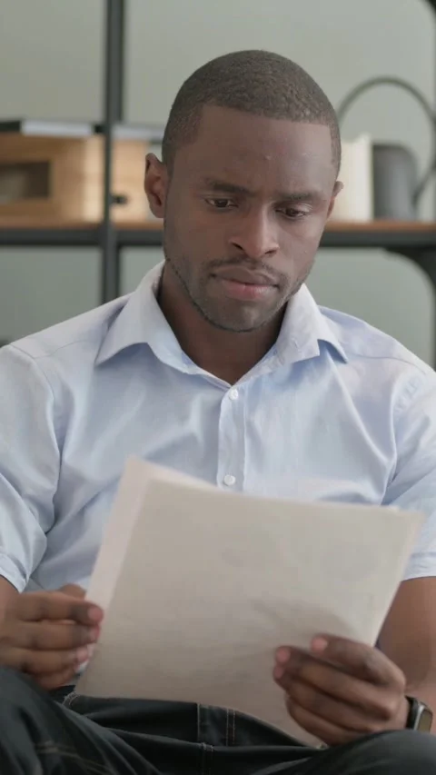 African Man Doing Paperwork while Sitting on sofa Stock Footage 301856451