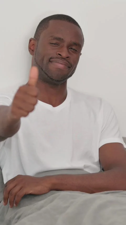 African Man doing Thumbs Up while Lying on Stomach in Bed Stock Footage 301855884