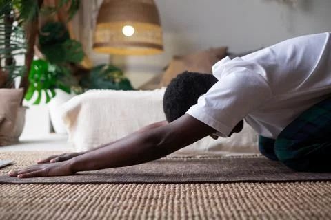 African man doing yoga at home, having rest in balasana or child pose, relaxing Stock Photos